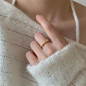 Close-up of elegant gold bow ring worn on hand with white knit sweater background