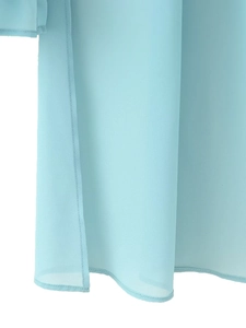 Detail of light blue chiffon top featuring a side slit and breathable fabric texture