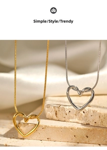 Detail of gold and silver hollow heart necklaces with sleek snake chains on stone background