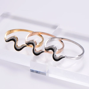 Detailed view of wave-shaped stainless steel bangles with crystal inlay in three colors