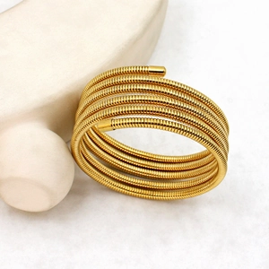 Close-up of 18K gold-plated stainless steel multi-layer spring cuff on marble surface