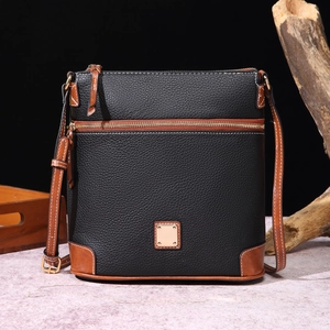 Close-up of black pebble leather crossbody bag featuring gold zippers and retro wood decor