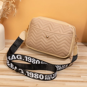 Detail of chevron quilted beige crossbody bag with adjustable wide woven shoulder strap