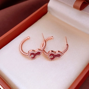 Macro shot of rose gold rope earrings with red enamel hearts and white zircon inlay