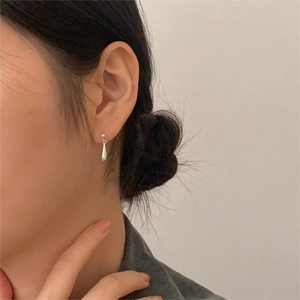 Primo piano dell'orecchino a goccia in argento sterling S925 indossato da una modella