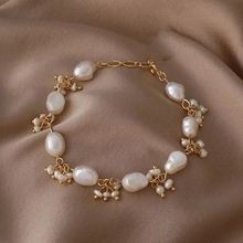 Detail of baroque freshwater pearl bracelet with golden chain on brown silk background