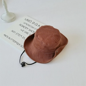 Detail of a brown outdoor bucket hat with adjustable black chin strap and metal buckles