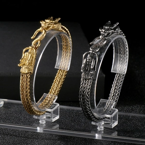 Detailed close-up of gold and silver dragon head bracelets with intricate metal weaving