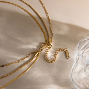 Close-up of 18K gold layered necklace showing S.Steel engraving and lobster clasp