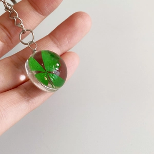 Macro shot of a handmade glass keychain featuring a real green four-leaf clover specimen