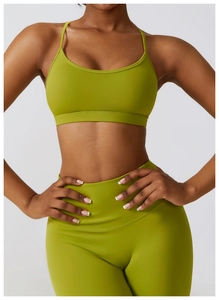 Detail of cross-back green yoga bra and high waist leggings with elastic dry-fit fabric