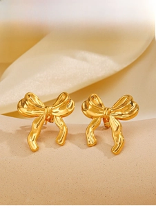 Gros plan de boucles d'oreilles nœud en acier inoxydable plaqué or 18 carats sur support