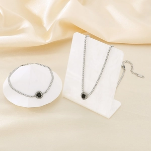 Detailed view of silver heart jewelry set with black gemstones and zircon on silk