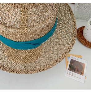 Detail of handmade straw sun hat with blue ribbon on white table in resort style
