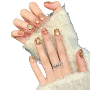 Handmade amber press-on nails with golden starburst, heart charms and fine glitter