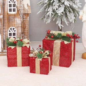 Three-piece red Christmas LED gift boxes with gold ribbons on a cozy rug decor