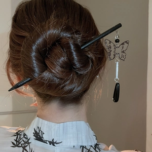 Detail of Chinese style hair pin with butterfly pendant and tassel on model's bun