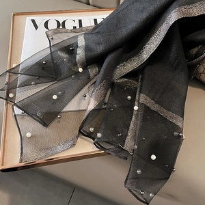 Detail of lightweight black mesh scarf with scattered white pearls and golden pinstripes