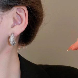 Close-up of wide silver-tone C-shaped hoop earrings with pave cubic zirconia on model