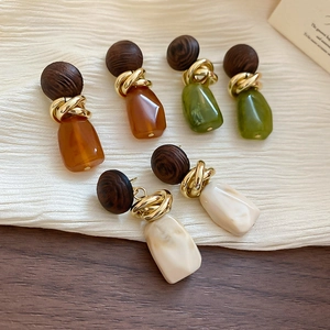 Détail de boucles d'oreilles en résine ambre, olive et crème avec accents en bois rétro
