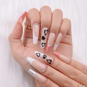 Detail of long French press-on nails with black hearts, glitter and rhinestone accents