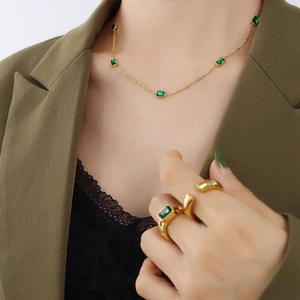 Gold necklace and ring set with emerald green zircon stones on elegant model