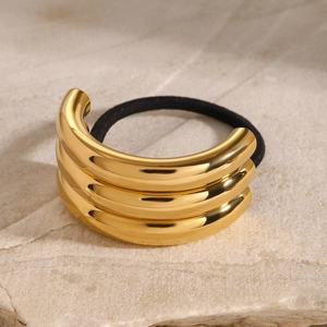 Golden triple-layered stainless steel ponytail holder on a minimalist stone background
