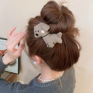 Close-up of a brown plush puppy hair claw clip styled on a woman's hair bun