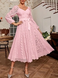 Gros plan d'une robe en dentelle rose avec taille ajustée et détail de nœud en ruban