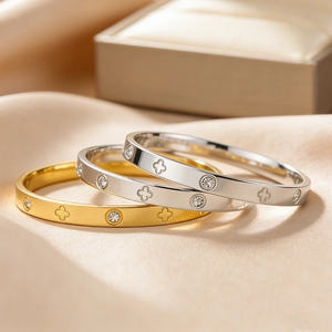 Trois bracelets en acier titane or et argent avec trèfles sur tissu de soie