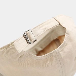Dettaglio posteriore regolabile di un berretto in cotone beige con fibbia in metallo e cuciture