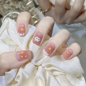 Close-up of nude pink press-on nails with cute yellow hearts, white clouds and star patterns