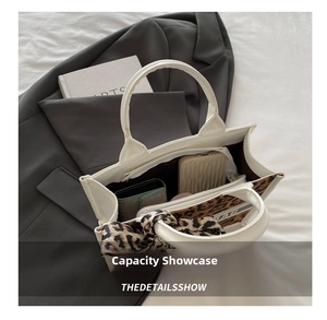 Interior detail of white tote bag with leopard print scarf and spacious storage capacity