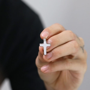 Macro shot of silver stainless steel cross pendant featuring white enamel inlay detail