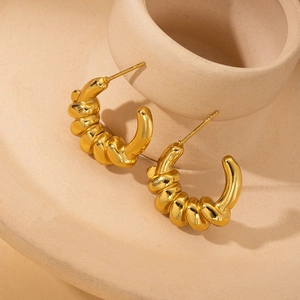 Elegant gold twisted croissant hoop earrings with polished finish on a stone display