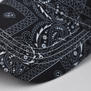 Detail of paisley print baseball cap showing white reinforced stitching on the black brim