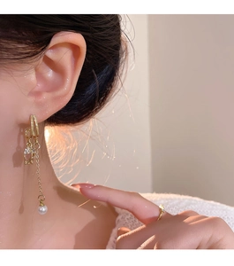 Detail of tulip long gold chain earrings with pearl pendant and matching gold ring