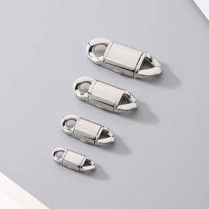 Macro view of four silver stainless steel fold-over clasps in varying sizes on grey surface