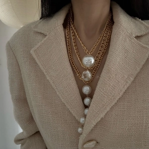 Detail of layered gold chain necklace featuring cascading white faux pearl pendants