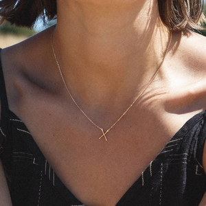 Collier en acier inoxydable plaqué or avec pendentif lettre X minimaliste porté par une femme