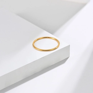 Minimalist 1mm gold titanium steel ring displayed on a modern geometric white pedestal