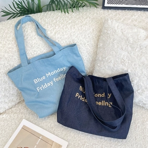 Dettaglio di borse tote in denim blu chiaro e scuro con testo Blue Monday Friday ricamato