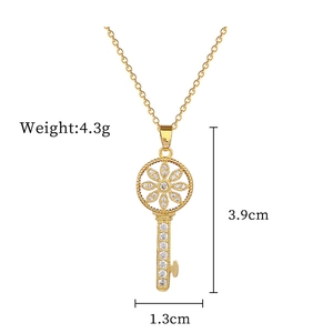 Detailed view of a gold key pendant with floral design and crystal inlay, 3.9cm height