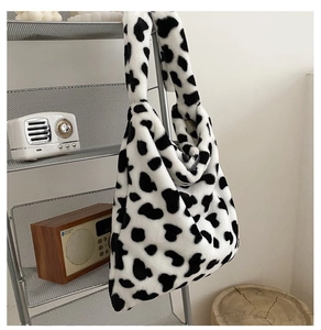 Detailed view of plush cow print tote bag hanging on a rack with soft texture focus