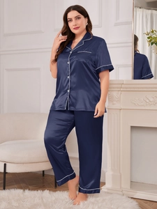 Detail of navy blue silk satin pajama set with contrast white piping on soft home background