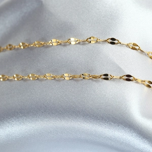 Macro detail of high-shine gold necklace featuring elegant leaf-shaped chain links