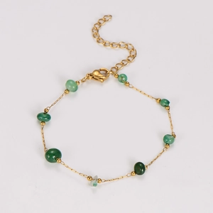 Close-up of gold chain bracelet with green emerald beads and lobster clasp closure