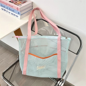 Detail of blue mesh beach tote bag with pink straps and orange pocket on chair