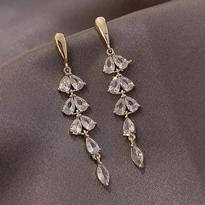 Detailed close-up of gold tassel earrings with teardrop rhinestones on fabric