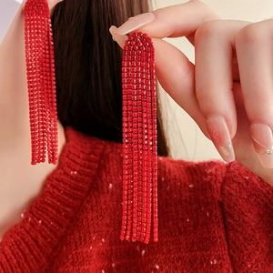 Detail of elegant red tassel earrings with sparkling rhinestones worn by a model